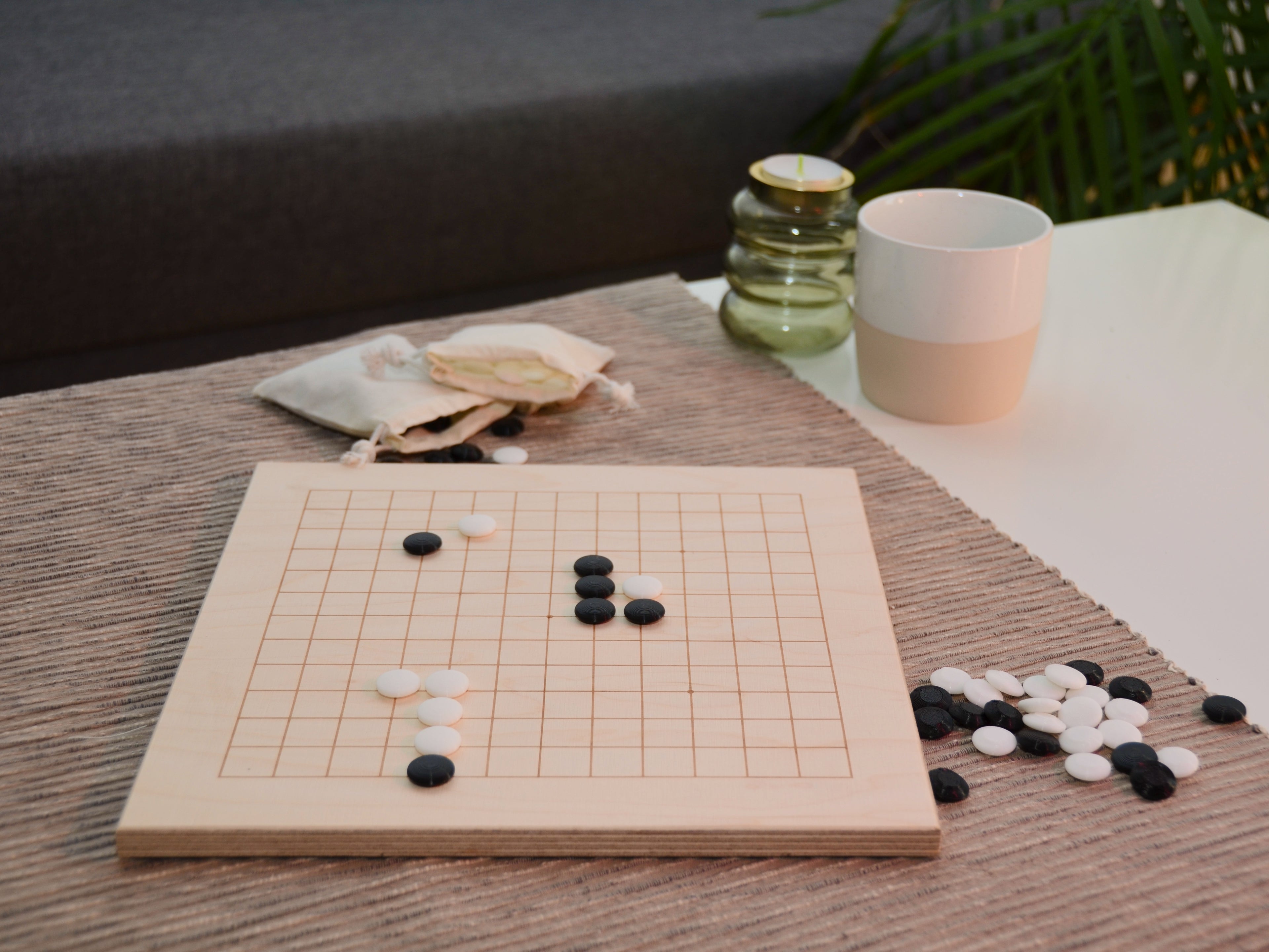 Baduk Holzbrett auf dem Tisch: Seitliche Ansicht des aufgebauten Spiels in wohnlicher Atmosphäre.