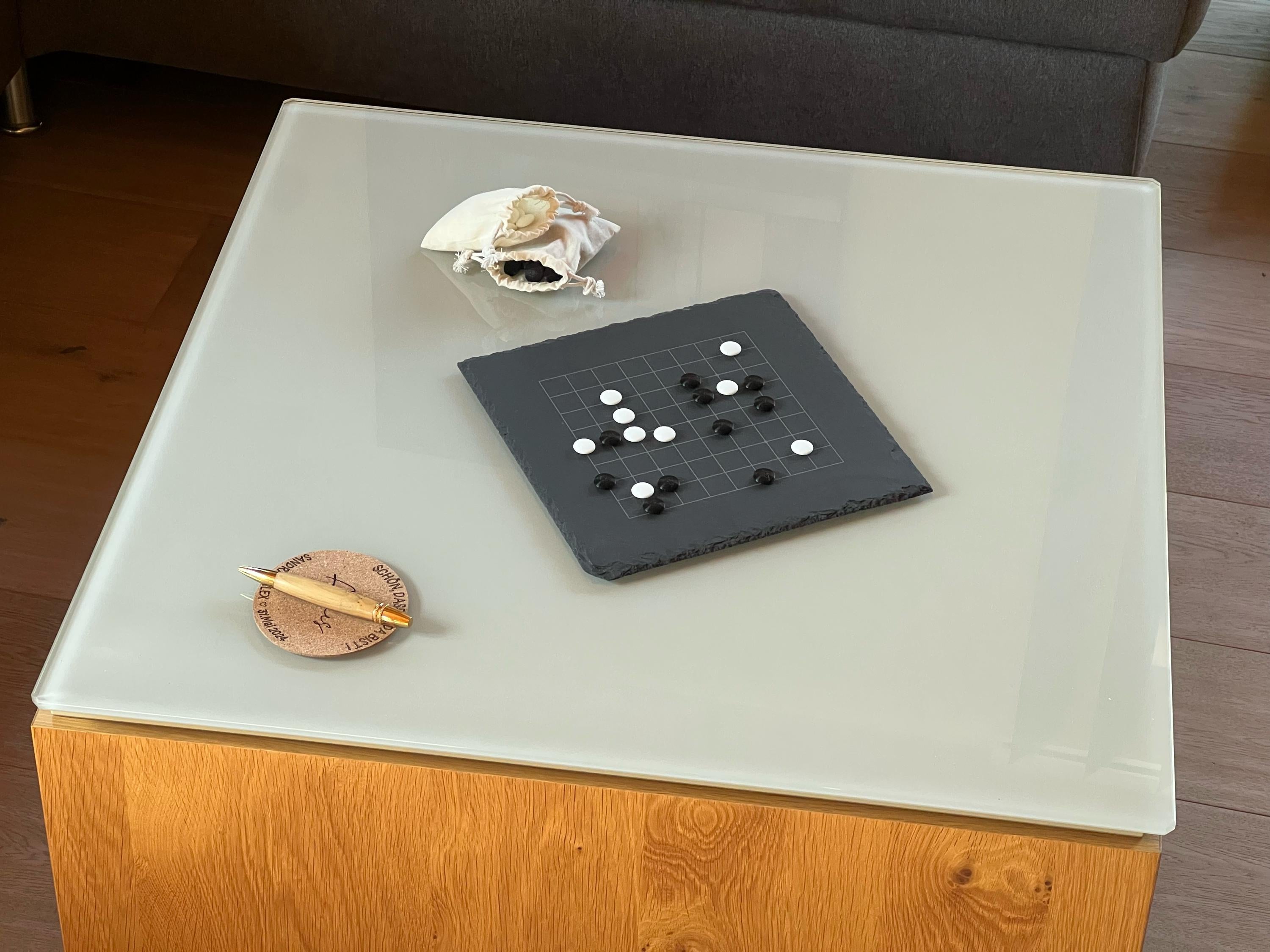 Kleines Go-Brett im Wohnzimmer: Edles Schiefer-Design dekorativ auf einem Glastisch platziert.