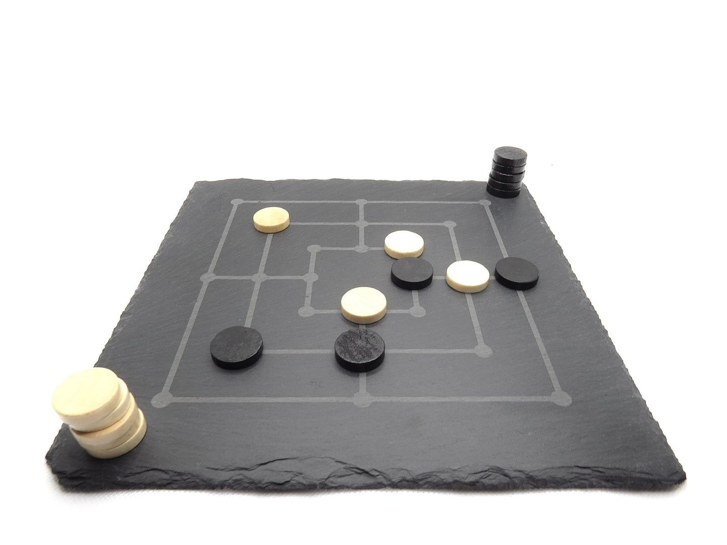 Mühle Spiel Set aus Naturschiefer: Lasergraviertes Brett mit schwarzen und weißen Spielsteinen im edlen Design.