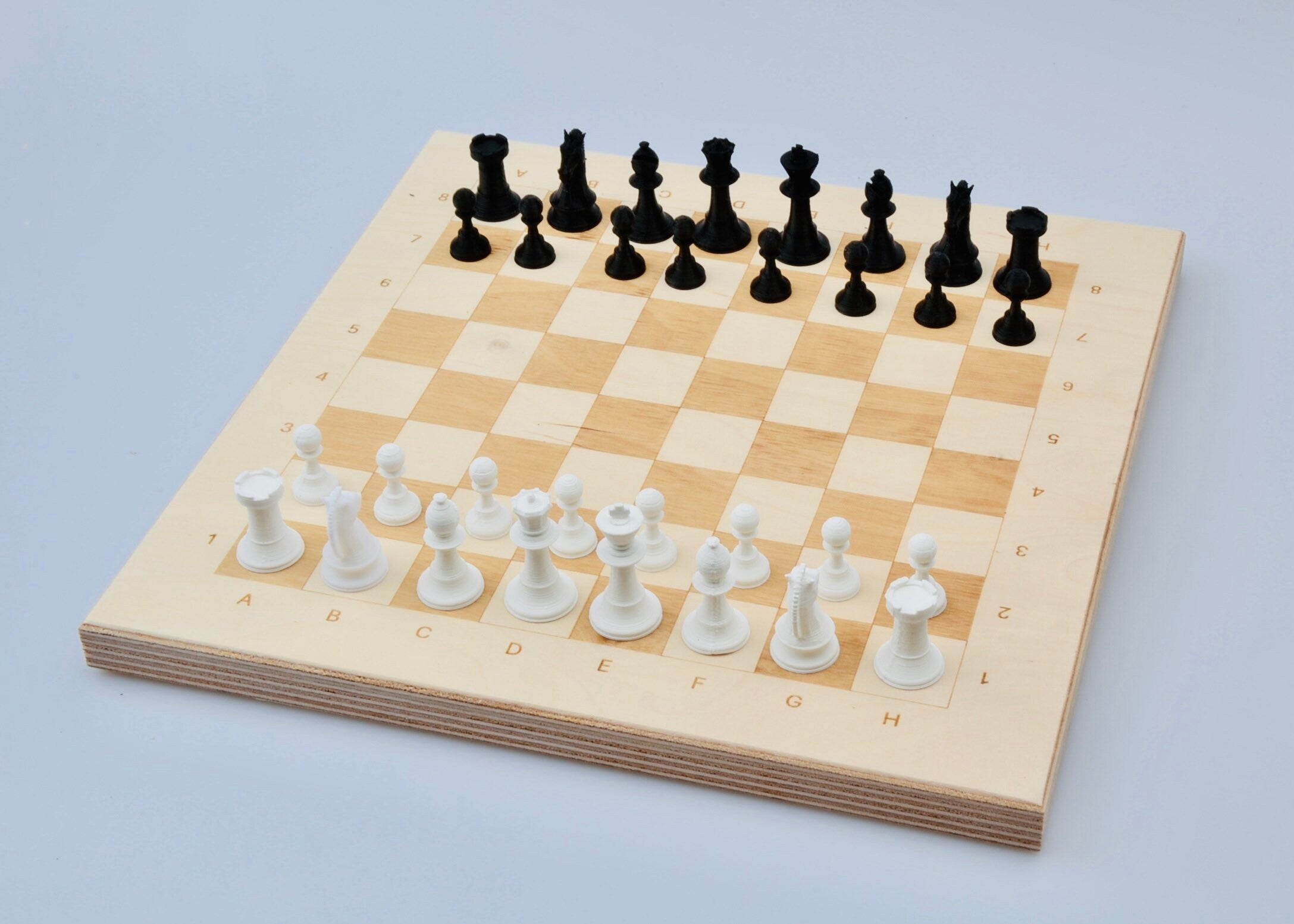 Schach spielen auf Holzbrett: Hand führt strategischen Zug mit weißer Figur auf dem lasergravierten Spielfeld aus.
