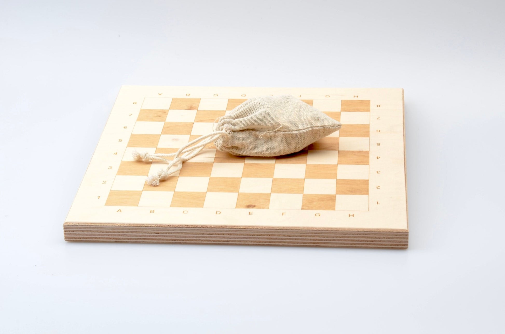 Zubehör für Holzschach: Praktischer Leinenbeutel zur Aufbewahrung der Figuren auf dem hellen Spielbrett.