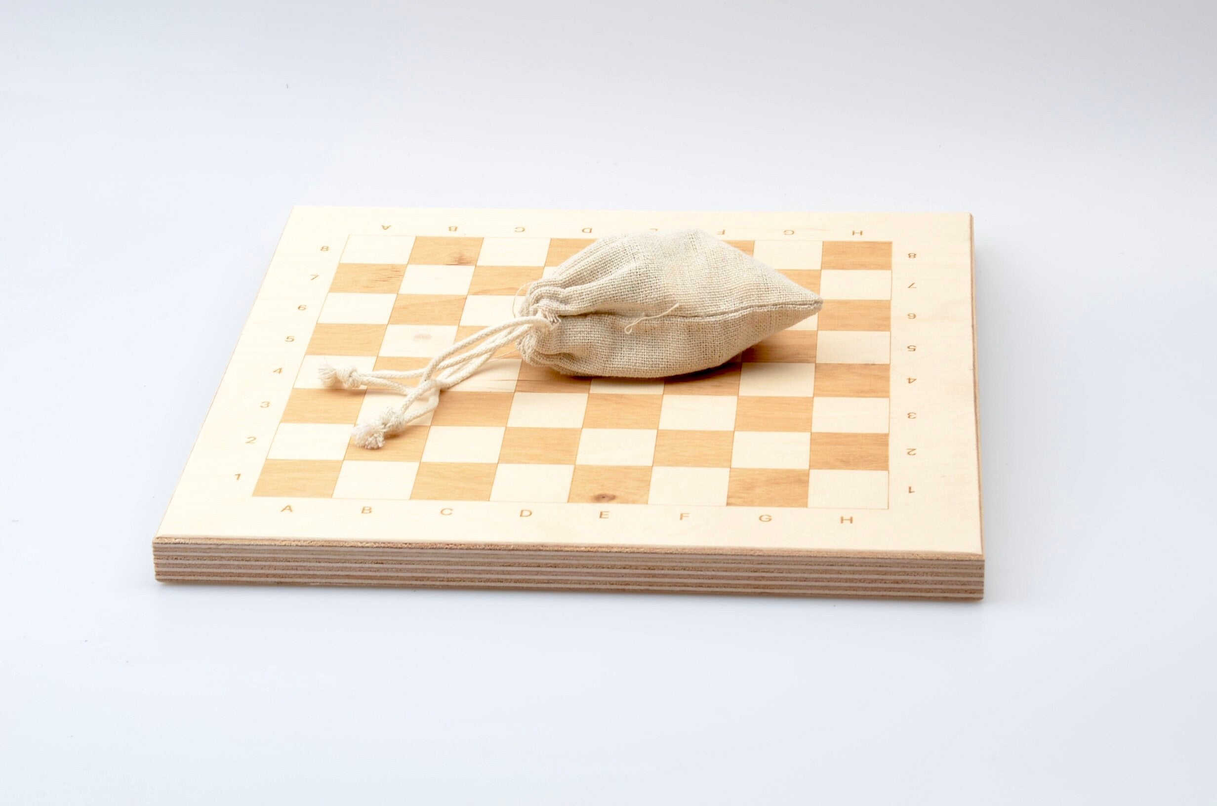 Zubehör für Holzschach: Praktischer Leinenbeutel zur Aufbewahrung der Figuren auf dem hellen Spielbrett.